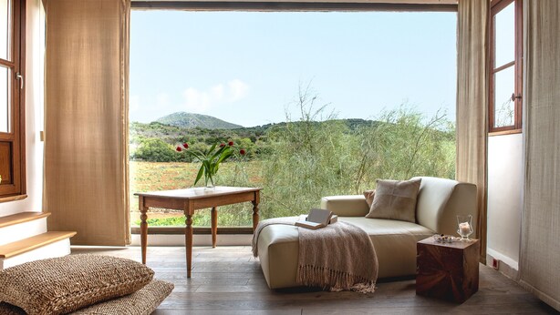 A cozy room with a sofa, a small table, and a view of a natural landscape. - Finca Sos Ferres D'en Morey (Manacor)