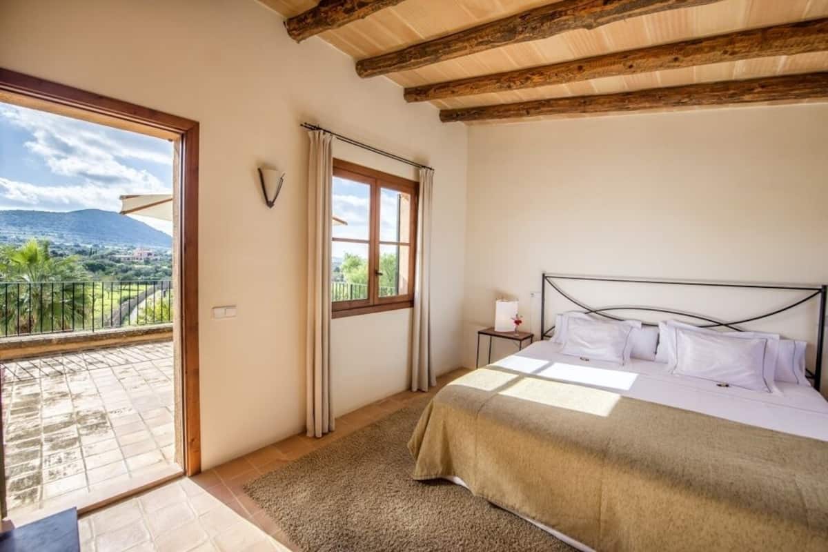Un dormitorio con cama, ventana y vista a un balcón.