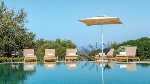 A poolside area with lounge chairs and an umbrella, surrounded by greenery and a clear sky. - Finca Sos Ferres D'en Morey (Manacor)