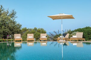 Una piscina al aire libre, sombrillas, sillones reclinables de piscina