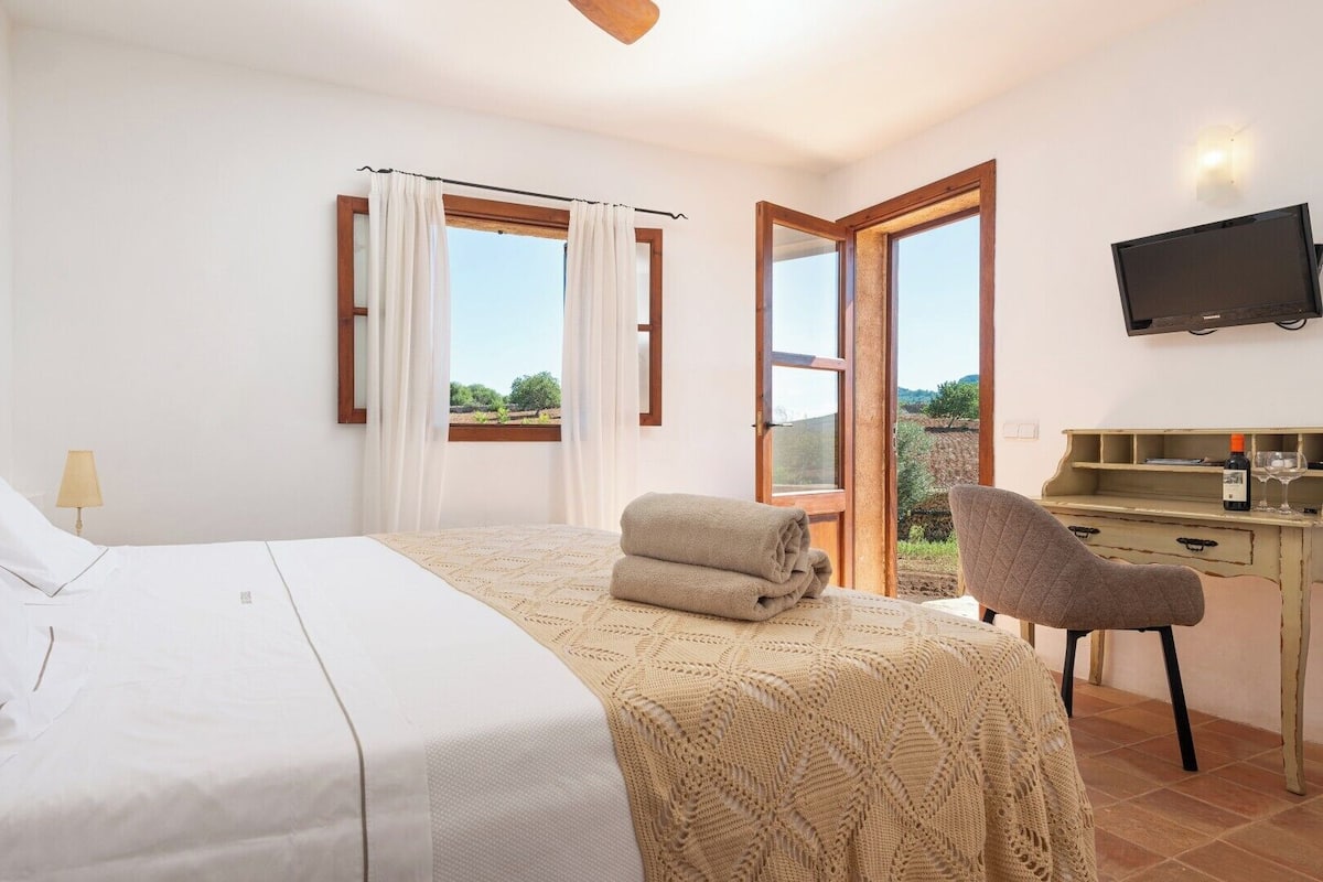 Un dormitorio con cama, escritorio, silla y televisor.