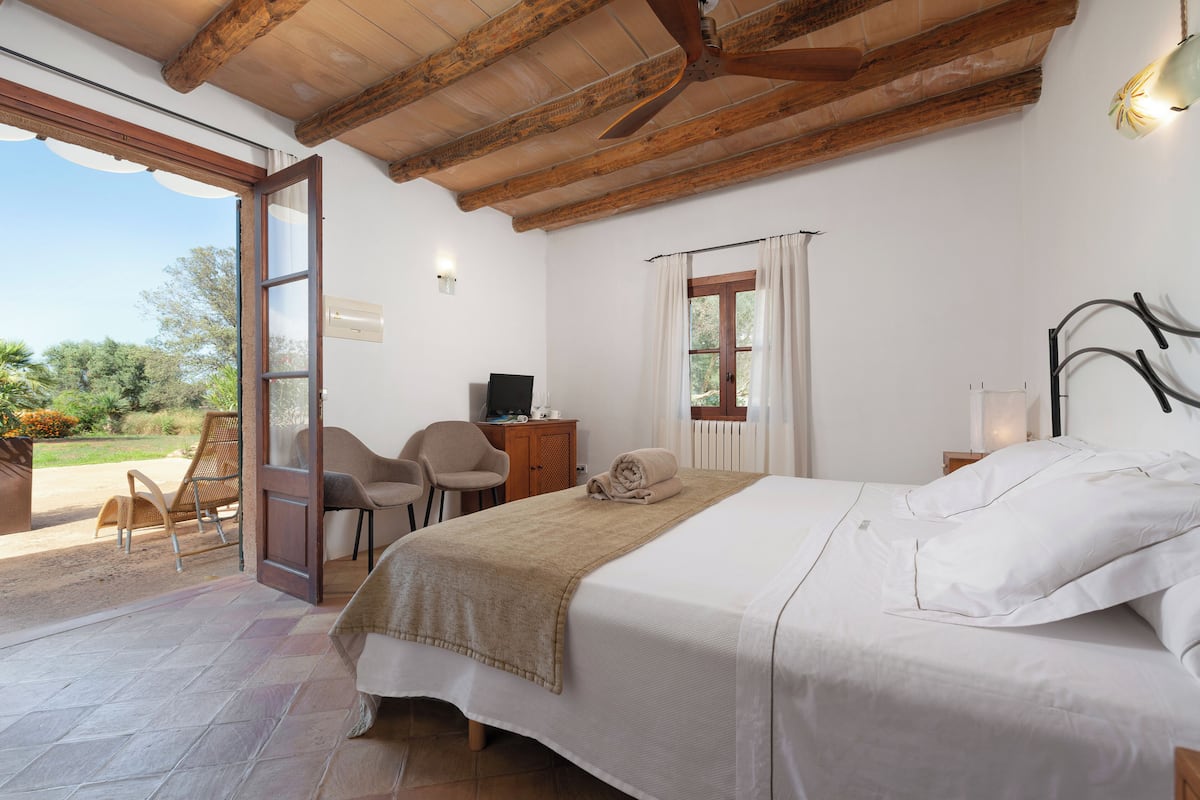 Un dormitorio con cama, escritorio, silla y vistas al exterior.