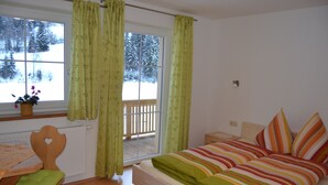 Une chambre à coucher avec un lit, une chaise, une fenêtre avec des rideaux et une vue sur un paysage enneigé.