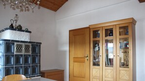 A dining area with a table, chairs, a cabinet with glass doors, and a wooden door. - FeWo Konstandin (Bischofsmais)
