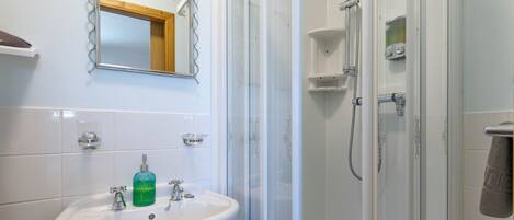 A bathroom with a white sink, a mirror, and a glass-enclosed shower.