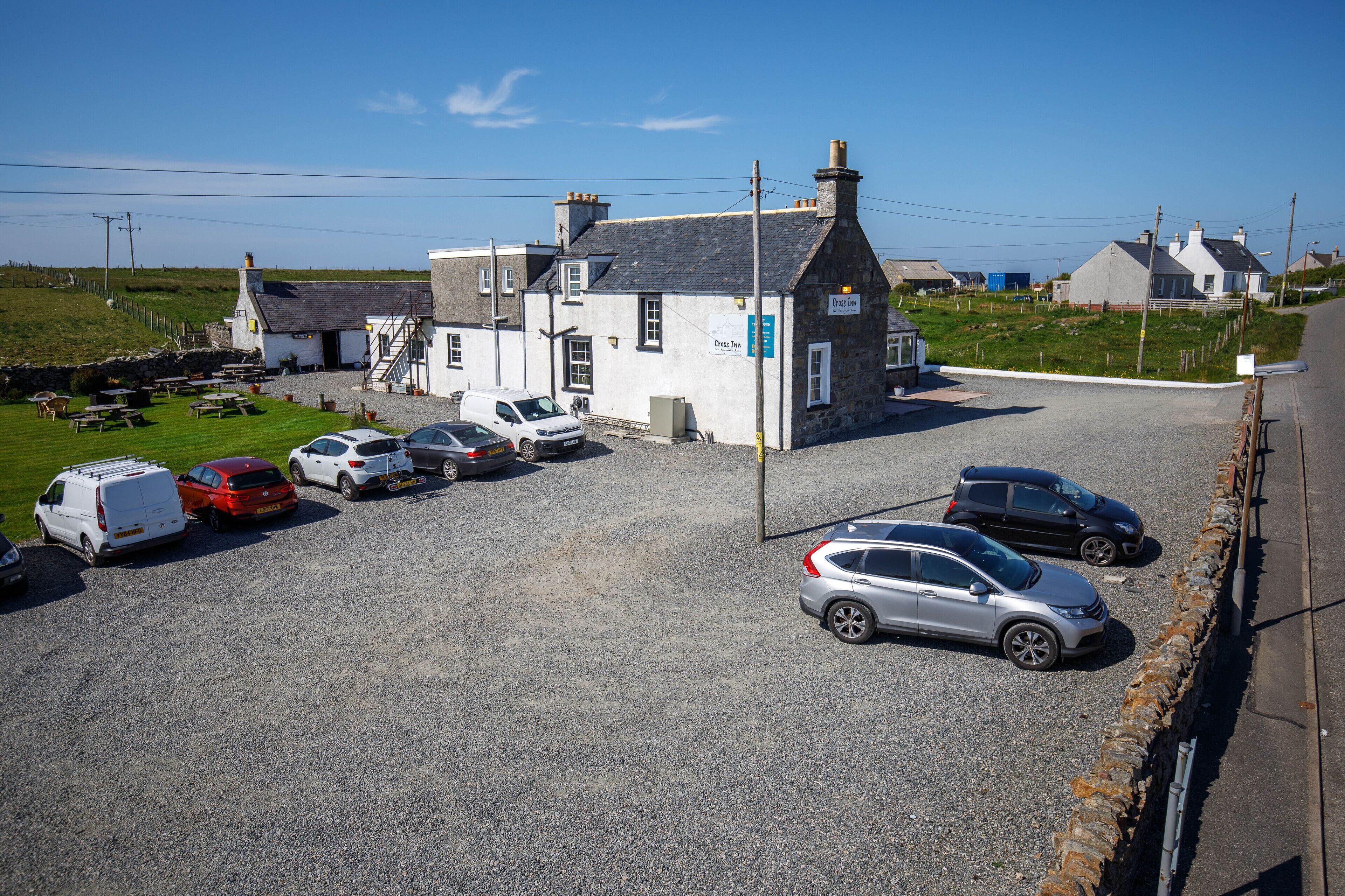 A parking lot with several cars and a white building with a sign that reads "Cressy Inn".