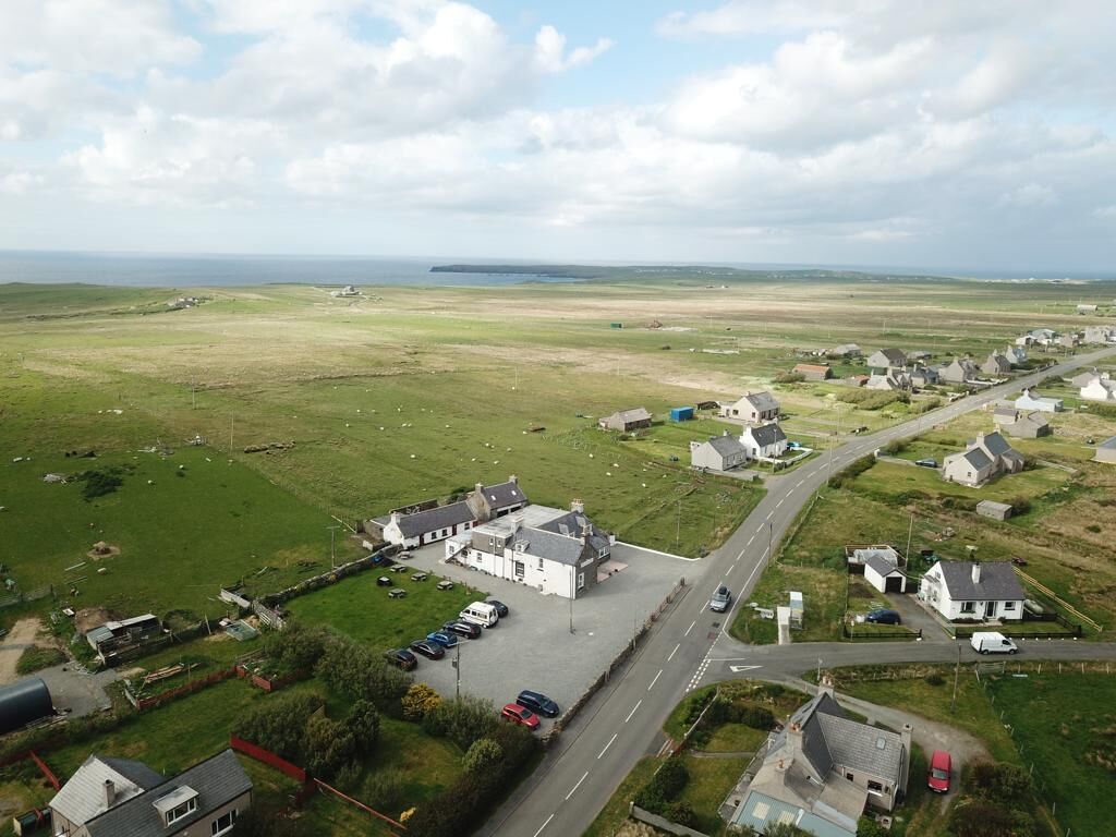 Luchtbeeld van een kustdorp met huizen, een hoofdweg en een parkeerplaats.