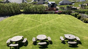 A well-maintained lawn with picnic tables and a stone wall. - Cross Inn (Isle of Lewis)