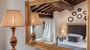 A bedroom with a large mirror, two bedside lamps, a bed with pillows, a nightstand, and a wall with circular mirrors.