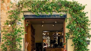 The entrance to La Boutique, featuring a wooden door, a green mat, and potted plants.