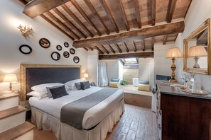 Ein Schlafzimmer mit einem großen Bett, Holzbalkendecke, Dachfenster und einem Nachttisch mit Lampe.