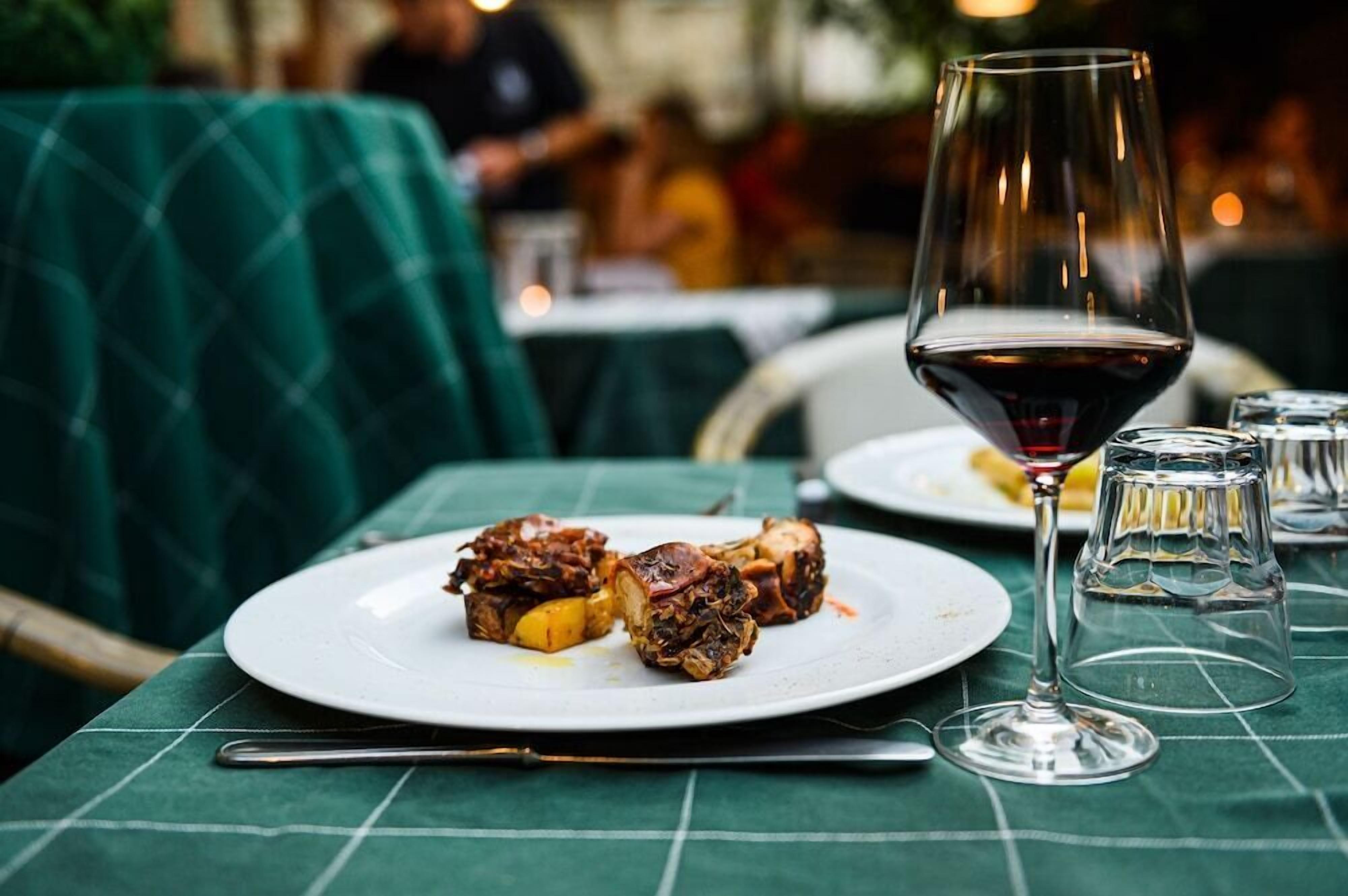 Une table à manger avec une assiette de nourriture et un verre à vin.