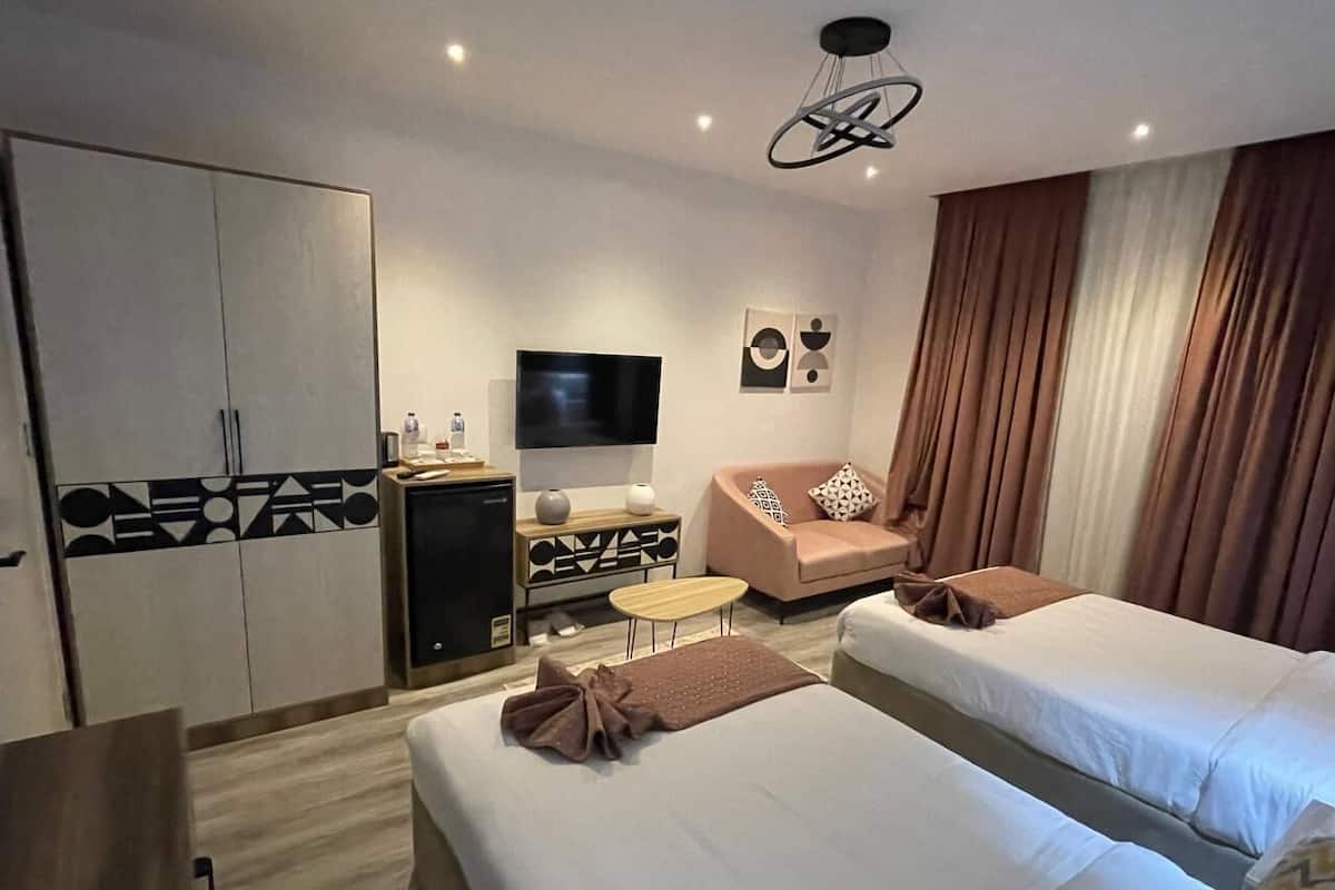 Hotellihuone, jossa on kaksi sänkyä, televisio, työpöytä ja vaatekaappi.