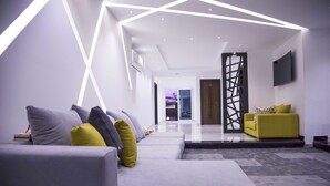 A modern living room with a grey sofa set, a yellow armchair, and a geometric ceiling design. - Elite Pyramids Boutique Hotel (Giza)