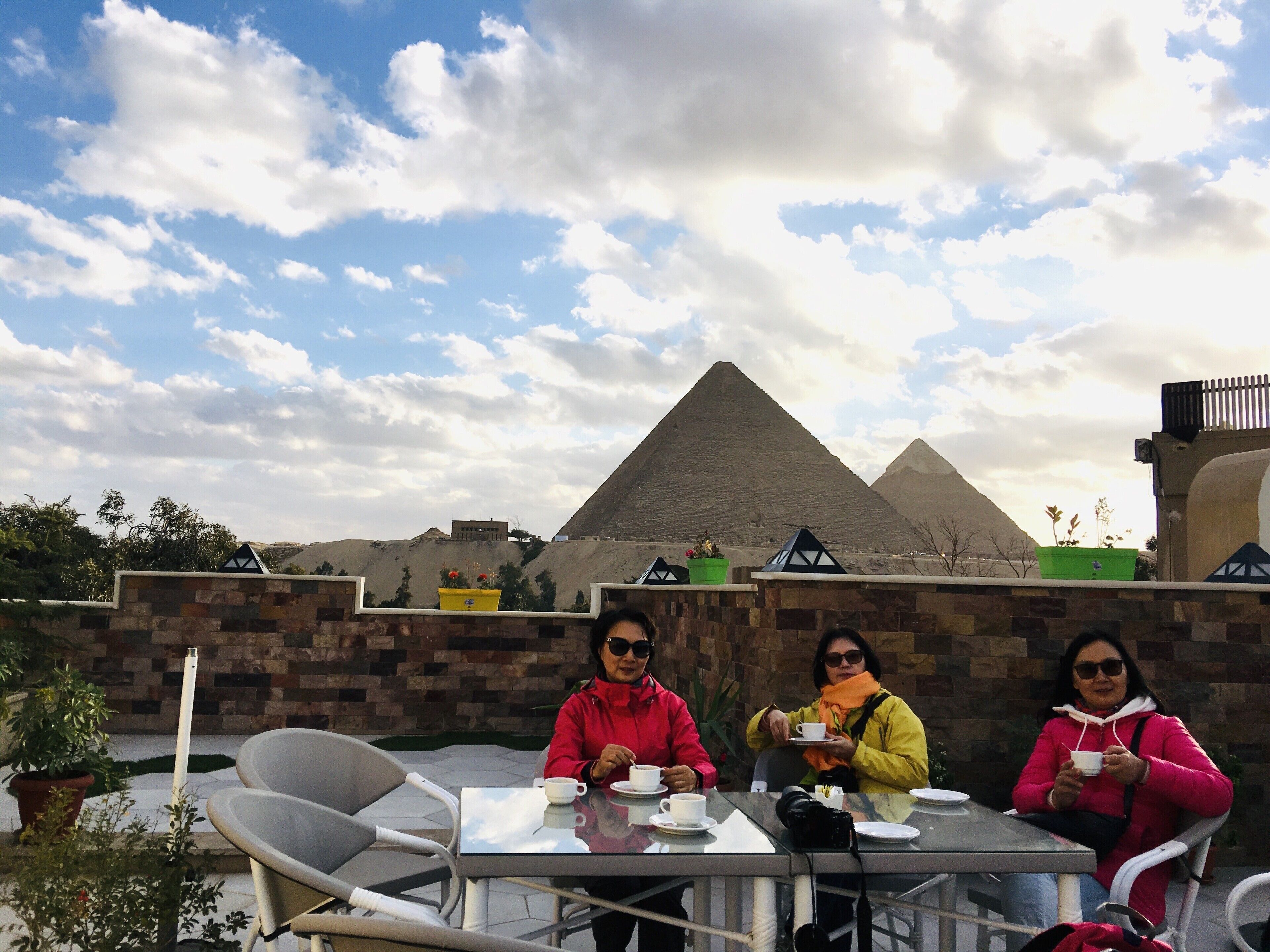 Three people seated at a table with a view of pyramids in the background.