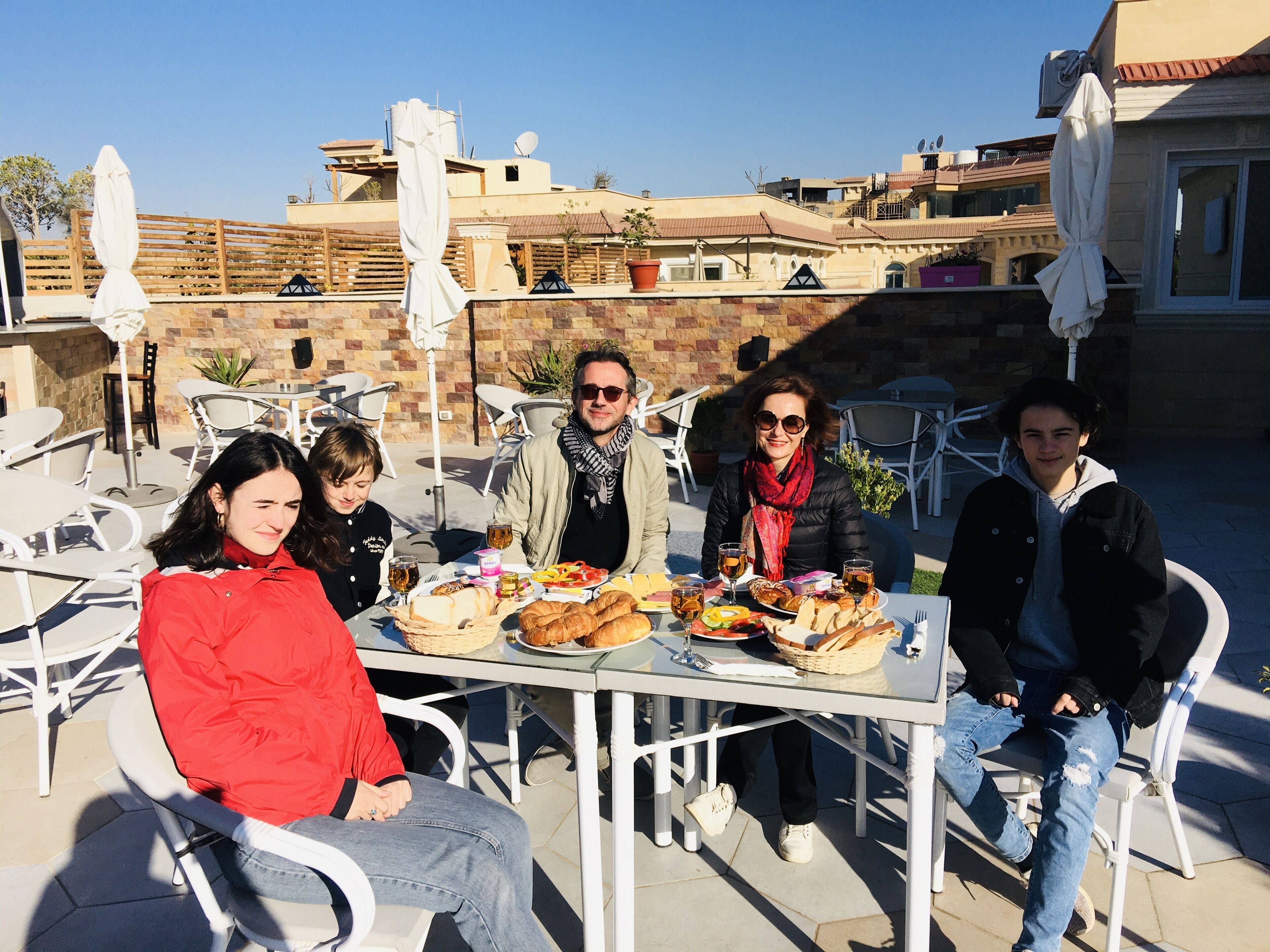 A group of people dining outdoors at a table with various dishes and drinks.