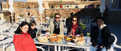 A group of people dining outdoors at a table with various dishes and drinks.