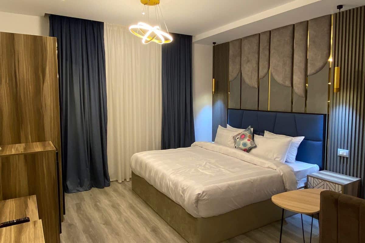 Una habitación de hotel moderna con una cama grande, un armario de madera, un escritorio y una silla.