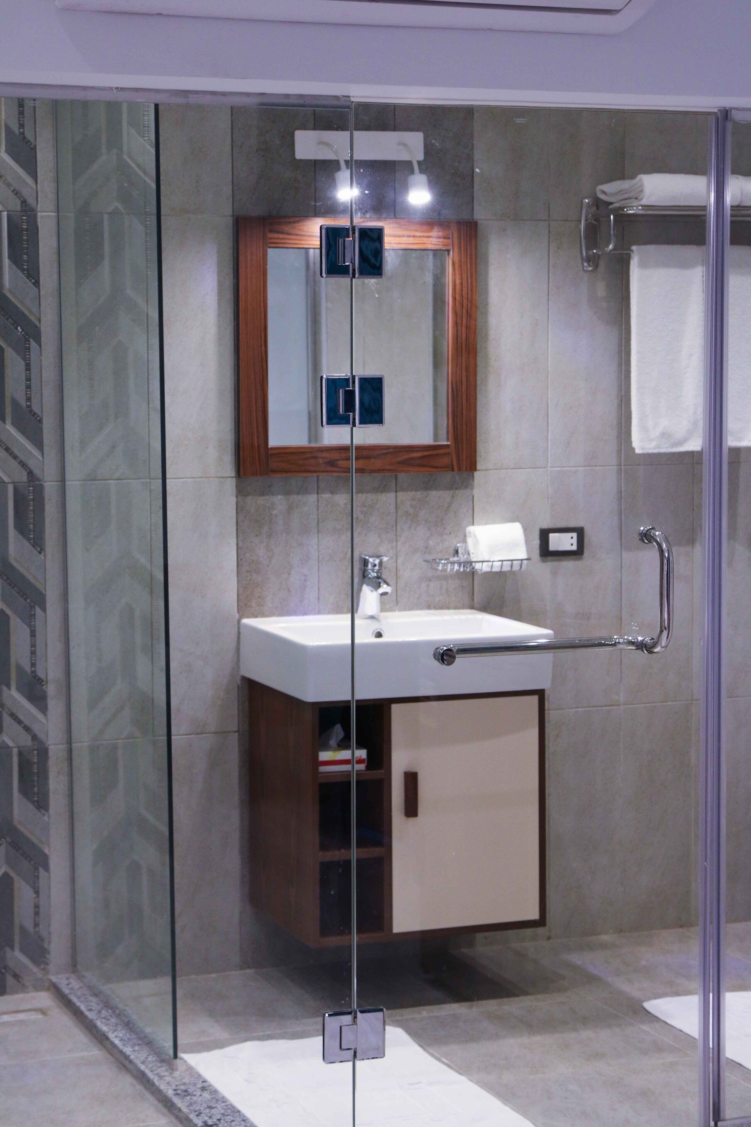 A modern bathroom with a glass-enclosed shower, a wooden cabinet, and a white sink.