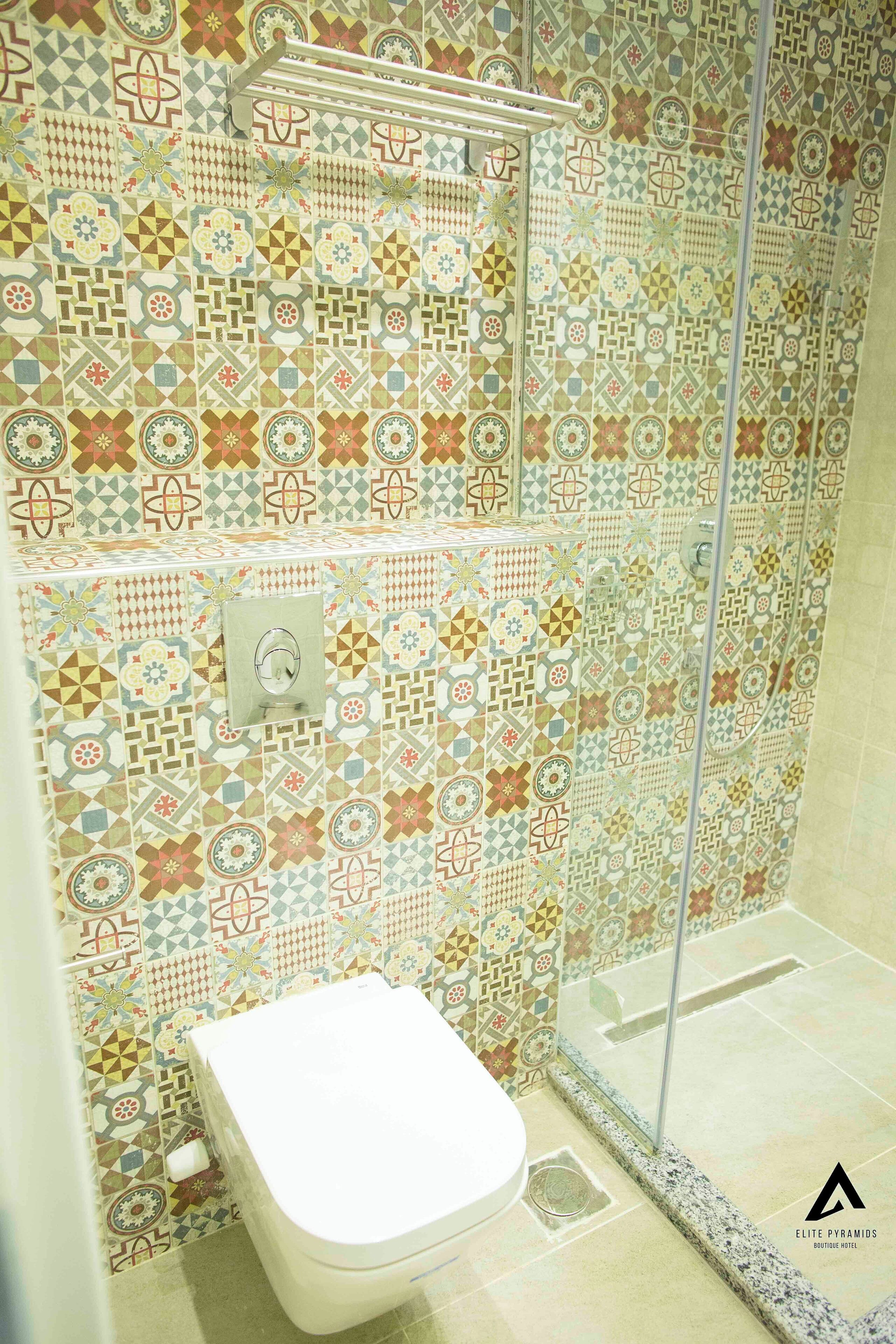 Une salle de bain avec un mur recouvert de carreaux à motifs, des toilettes et un espace douche.
