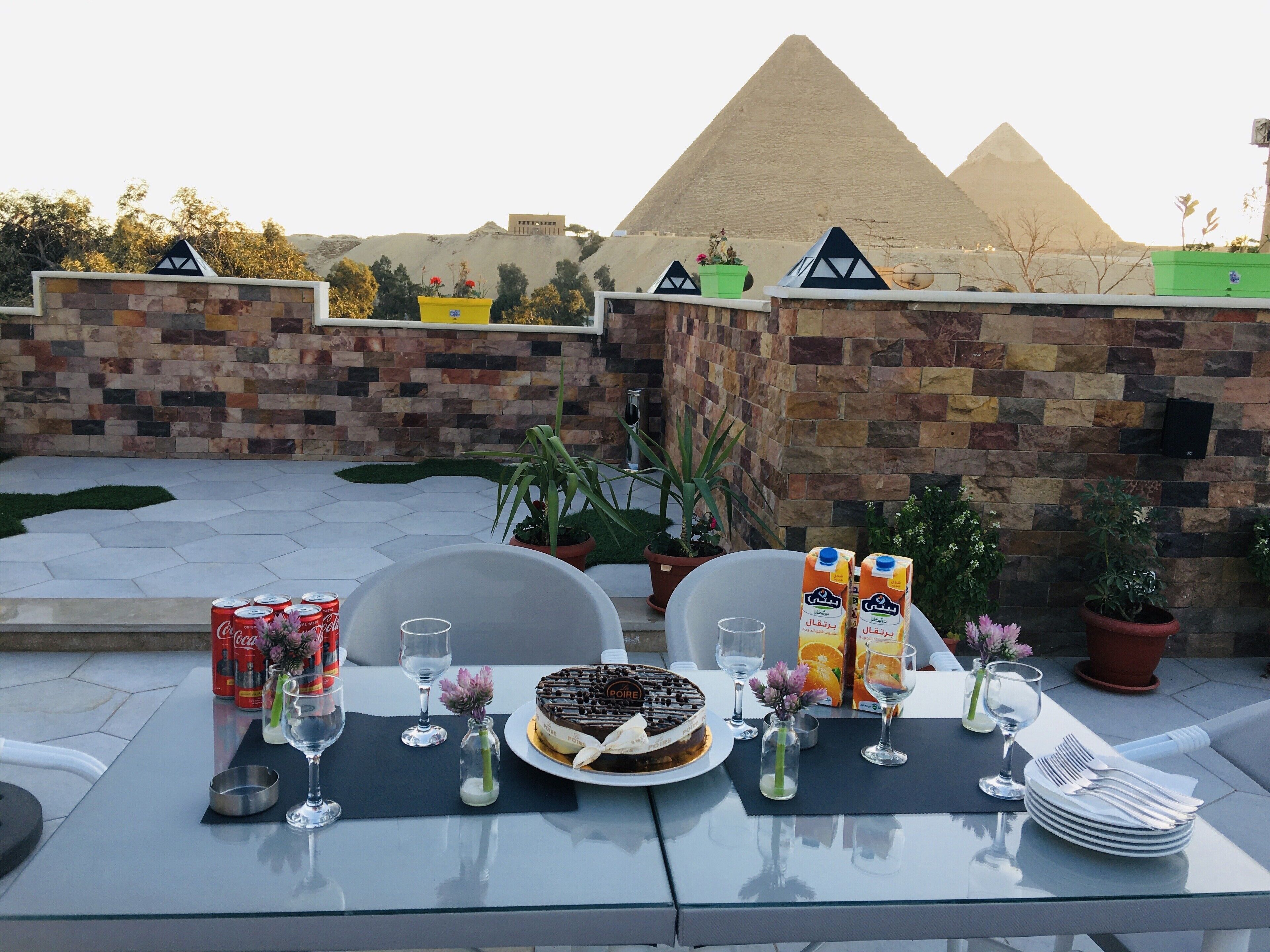 Mesa exterior con un pastel, bebidas y vistas a las pirámides.