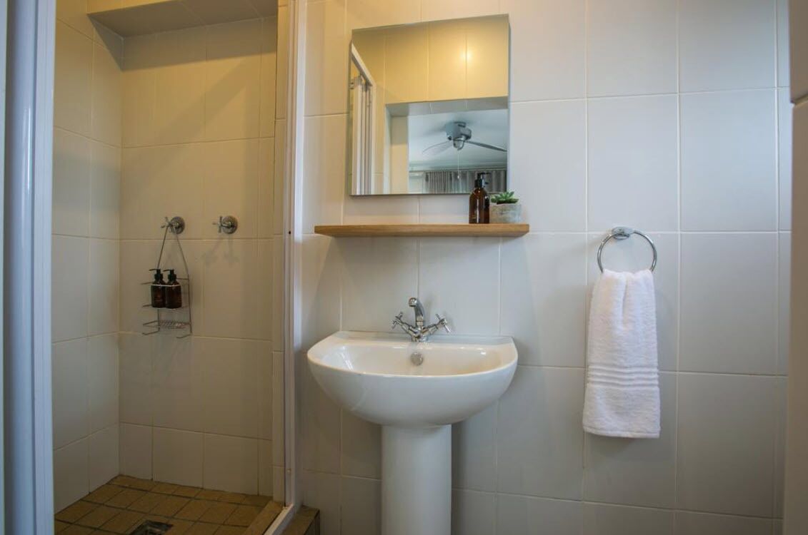 Ein Badezimmer mit Dusche, Waschbecken, Spiegel und Handtuchhalter.