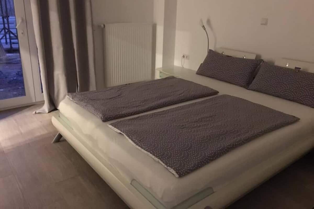Ein Schlafzimmer mit einem Bett, einem Heizkörper und einem Fenster mit Vorhängen.