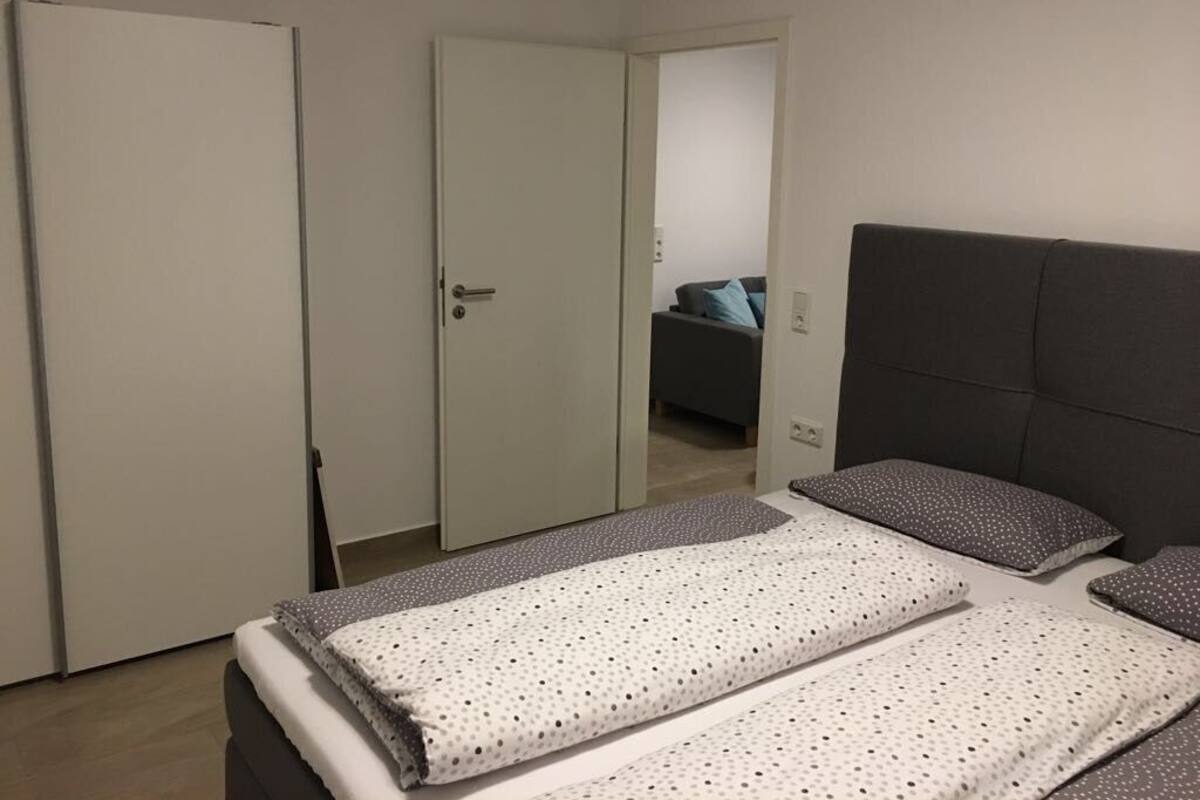 Ein Schlafzimmer mit Bett, Kleiderschrank und einer Tür zu einem anderen Raum.