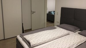 A bedroom with a bed, a wardrobe, and a door leading to another room. - Apartments am Moselufer (Bruttig-Fankel)