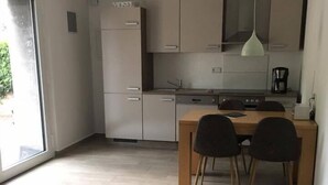 A modern kitchen with a dining area, a small round table, and a sofa. - Apartments am Moselufer (Bruttig-Fankel)