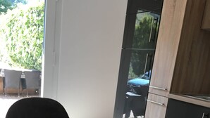 A modern kitchen with a wooden table, a white vase, and a view of a car outside. - Apartments am Moselufer (Bruttig-Fankel)