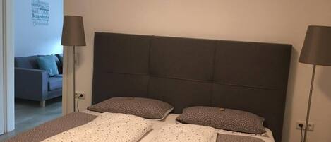 A bedroom with a large bed, two bedside tables, and a headboard.
