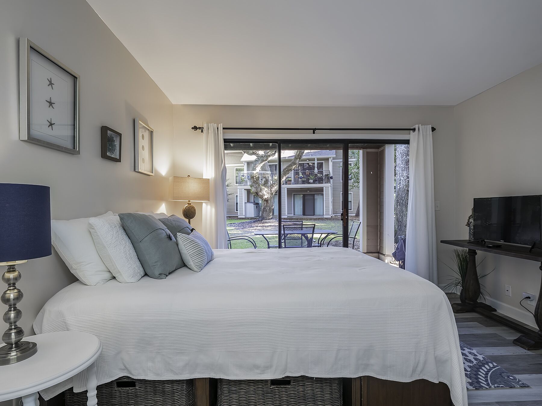 Une chambre à coucher avec un lit, une télévision, une lampe et une vue sur l’extérieur.