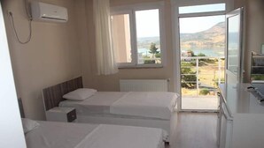 A hotel room with two beds, a window with a view of a landscape, and an air conditioning unit on the wall. - Otel Gerger (Gerger)
