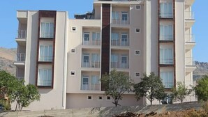 A multi-story residential building with balconies, a central stairwell, and a flat roof. - Otel Gerger (Gerger)