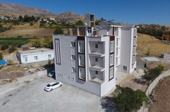 Um edifício residencial moderno de vários andares, com telhado plano, varandas e área de estacionamento.