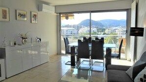 A modern apartment with a balcony, a dining area, and a living room. - Apartment "Le Jean Bart" with pool and views of Cannes Marina (Mandelieu-la-Napoule)