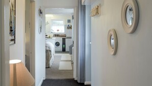 A hallway leading to a laundry area with a washing machine, dryer, and a small table with a lamp.