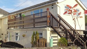 A two-story building with a balcony, a staircase, and a small garden area.
