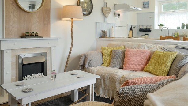 A cozy living room with a fireplace, a white table, and a sofa with patterned cushions.