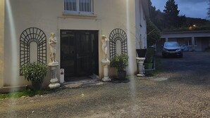 Un edificio con una puerta negra, dos estatuas y un coche estacionado en la entrada.