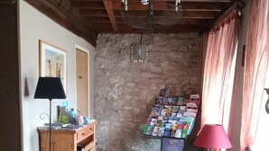 Una habitación acogedora con un escritorio de madera, una silla, una lámpara, una estantería y un expositor de revistas en la pared.