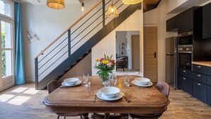 Una cocina moderna con armarios oscuros, horno empotrado y comedor con mesa de madera para cuatro.