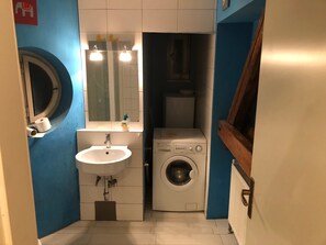 A compact bathroom with a sink, mirror, toilet, and washing machine. - Alher Apartma (Ljubljana)