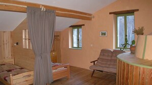Una habitación acogedora con una cama de madera, una silla, una mesita y un ventanal con vistas.