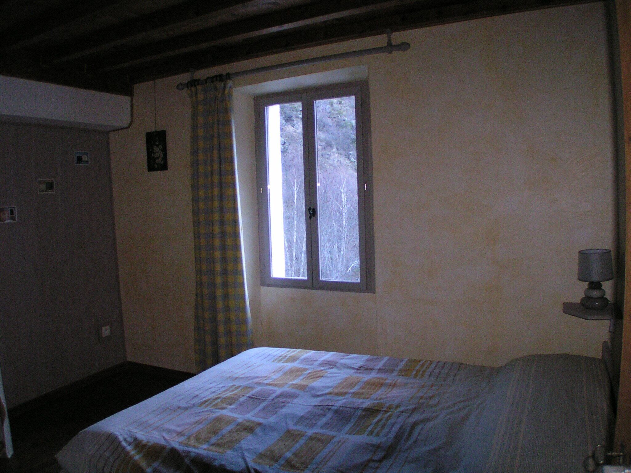 A bedroom with a bed, a window, a lamp, and a door.