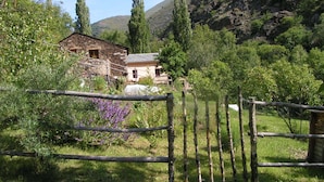 Una casa de piedra rústica con un cerco de madera en un valle exuberante y verde.
