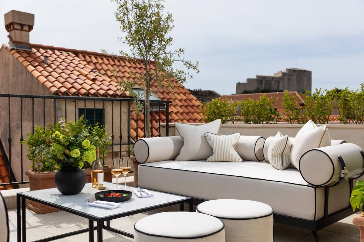 A rooftop terrace with a sofa, table, and potted plants.