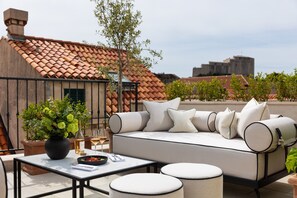 Terraço no telhado com sofá, mesa e plantas em vasos.