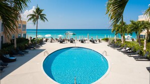 Zona de piscina amb gandules i sombreretes, una piscina blava cristal·lina i vista a l'oceà.